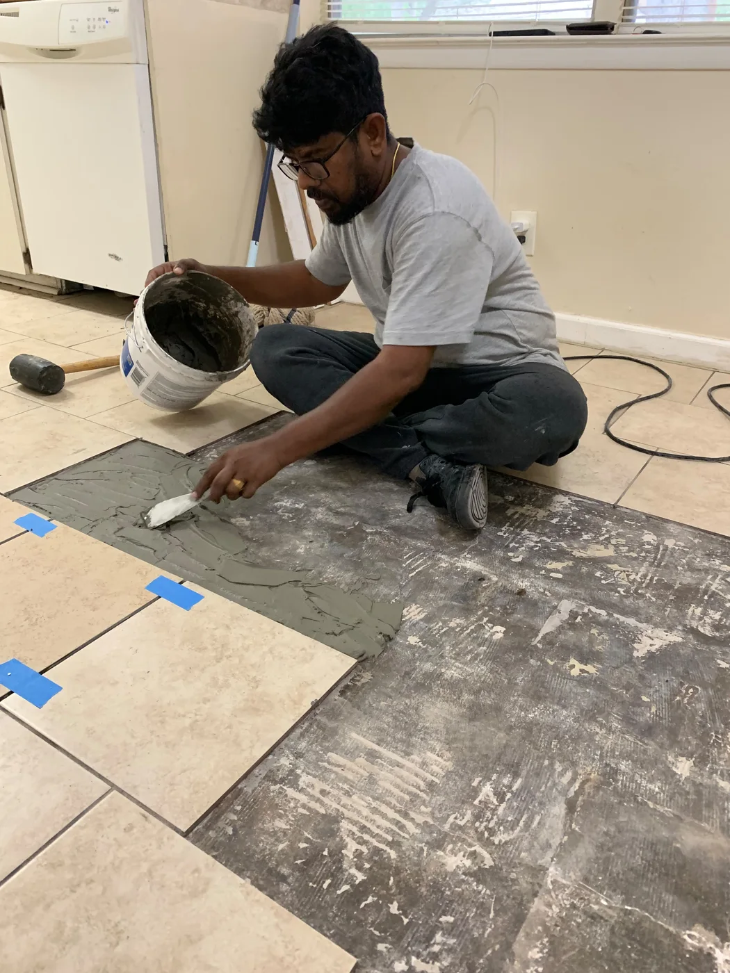 Dad spreading mortar during a floor tile project, with the existing floor and work area visible